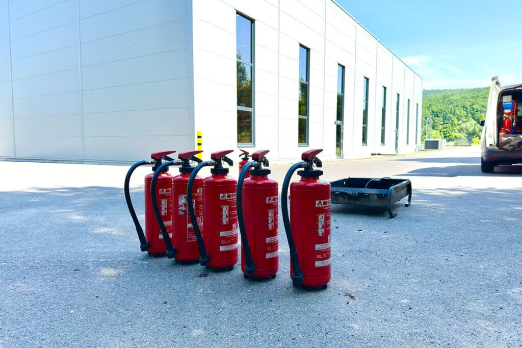 Mehrere Feuerlöscher vor einem Firmengebäude – Symbol für vorbeugenden Brandschutz in Unternehmen
